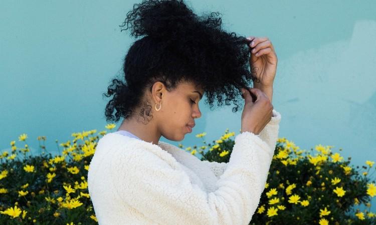 Lockdown afro hair care: Black woman looking down while touching hair