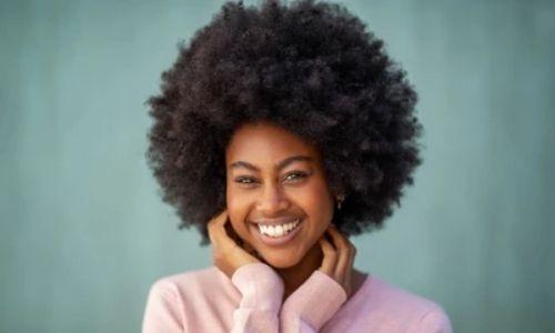 beautiful black woman wearing a pink jumper with large afro smiling