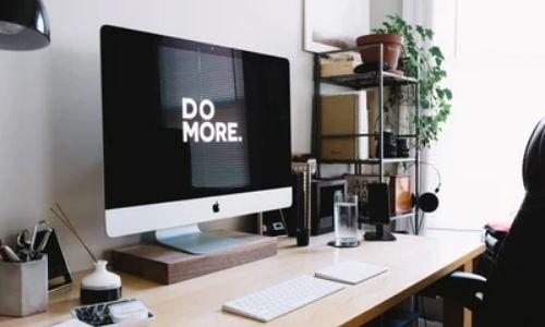 Home office set up with a Mac that has the words 'do more' on the screen