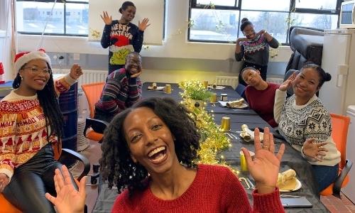 Happy smiling black women at the table: Christmas picture of the Afrocenchix team