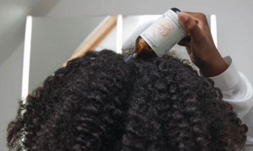 Woman applying Afrocenchix scalp oil on scalp 