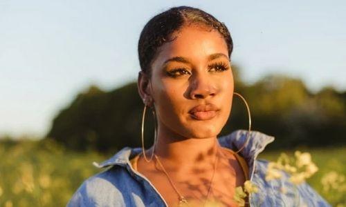 young black woman with large hoop earrings standing in a field in summer