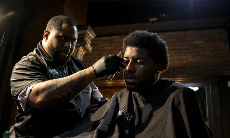 young black man getting his hair trimmed by a black barber