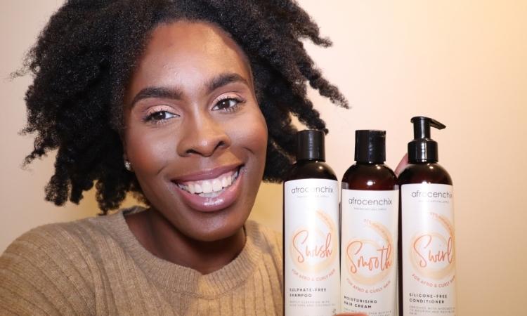 5 Tips For Being Confident Wearing Your Natural Hair Josephine smiling with Afro hair and holding Afrocenchix products
