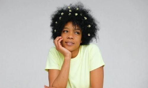 Natural Haired woman with flowers in hair wearing green T-shirt