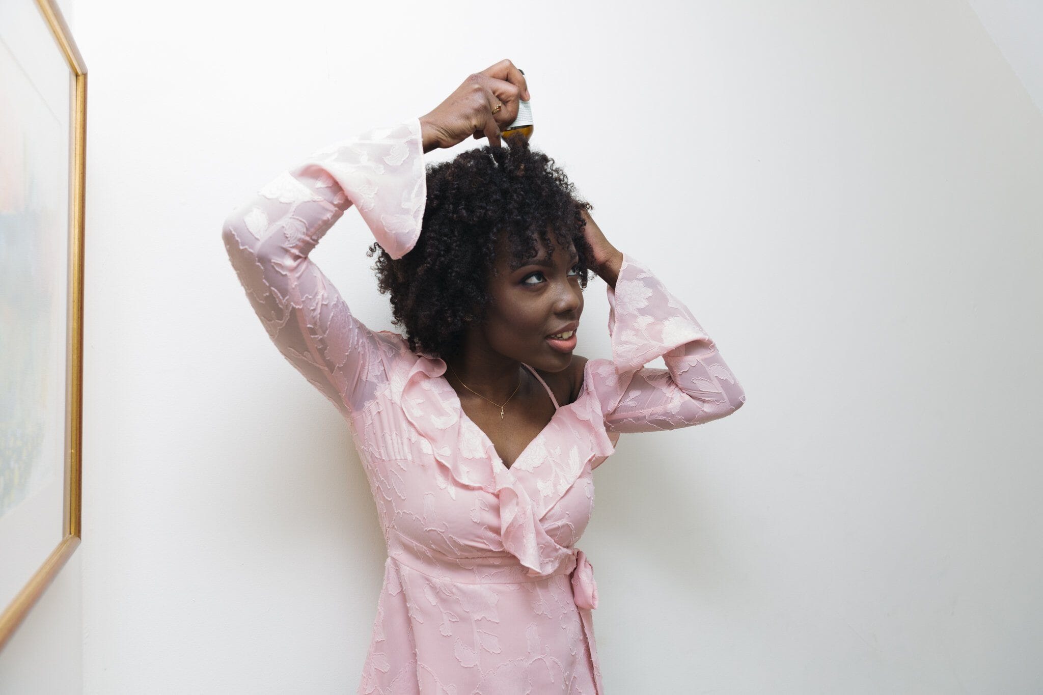 lady with afro hair applying hair oil 