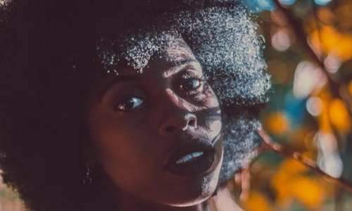 Dry scalp: Close up of a Black woman standing autumnal trees