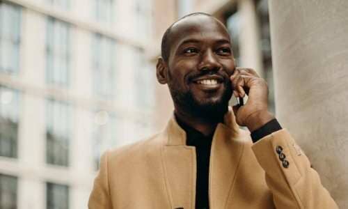 Afrocenchix mens hair loss article black men with short shaved hair smiling on a mobile phone 