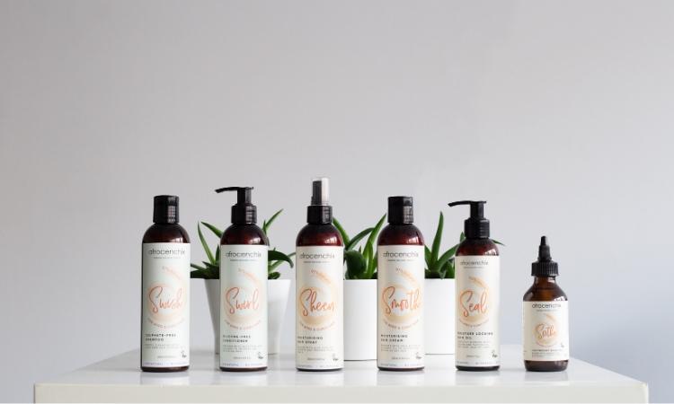 Full set of Afrocenchix products on a white table in front of a plant