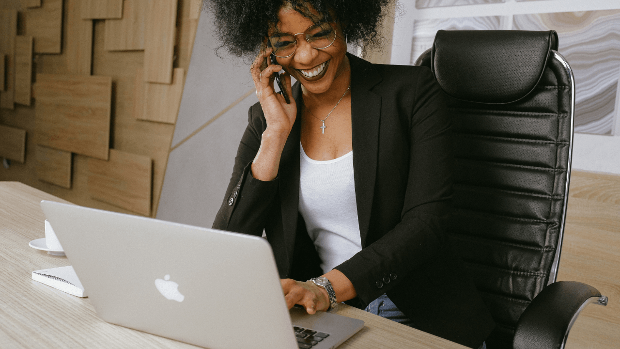 Photo of Black Woman Using Laptop on the Phone Smiling by Anna Shvets from Pexels