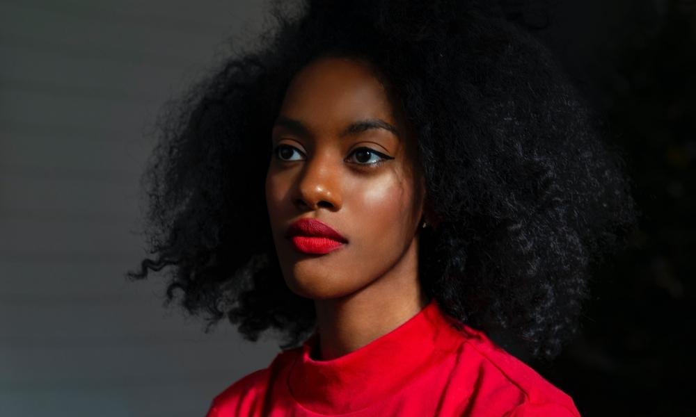 Afrocenchix article: Why Is My Natural Hair So Dry? Black woman with red lipstick and top with dry hair