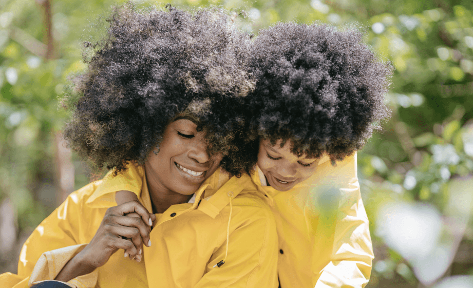 Black mother and child with coily Afro textured hair both wearing yellow raincoats