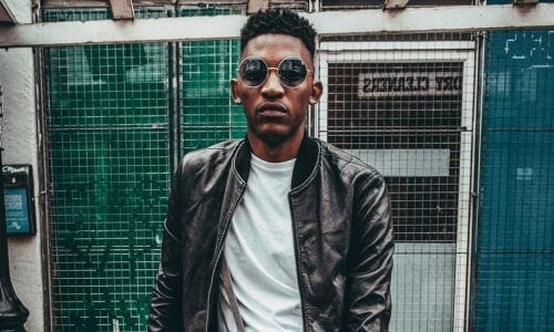 Afrocenchix how to care for men's curly and afro hair care article image: black and white picture of a handsome black man with short cropped afro hair and a beard wearing a T-shirt