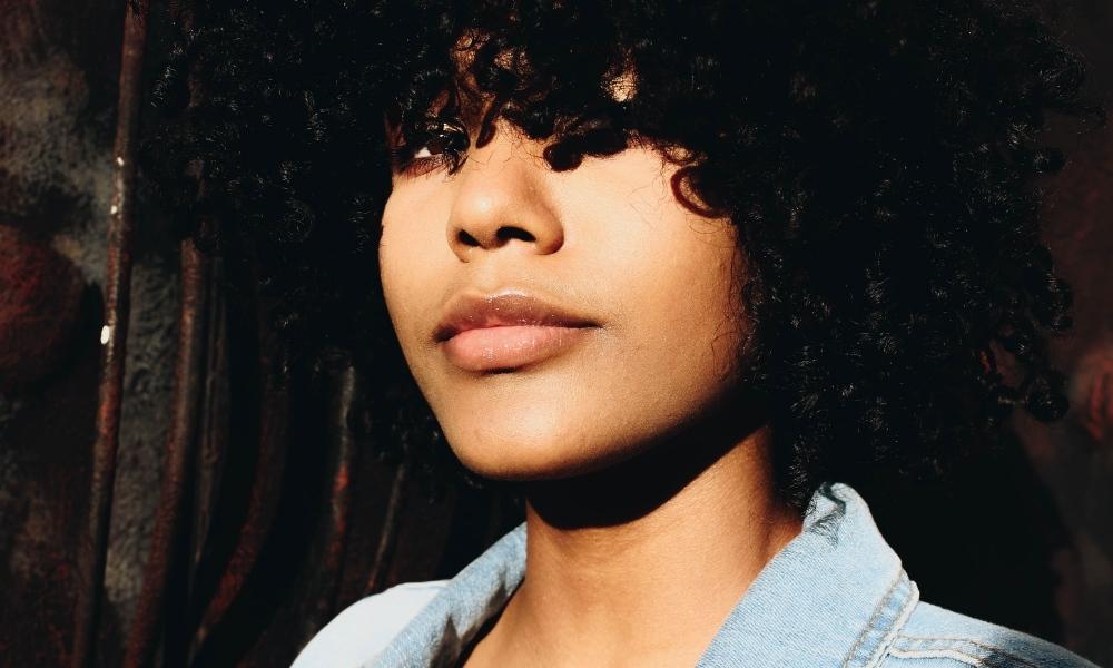 afro hair growth: Close up of a black woman with curly hair and fringe