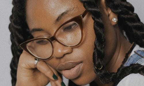 Repair Afro Hair Damage: woman with curly tucking her hair behind her ear
